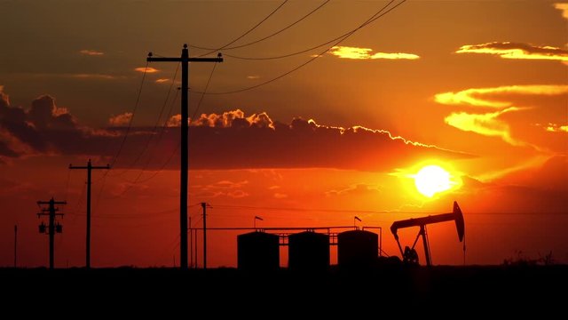 Oil pump jack containers and electrical wiring at amazing sunset