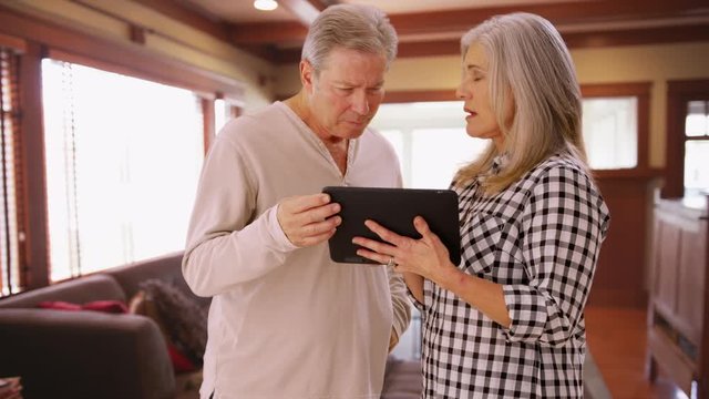 Charming mature couple looking at tablet computer