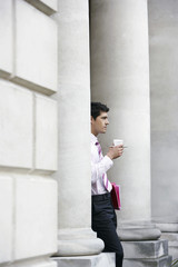 Young businessman having coffee outside building