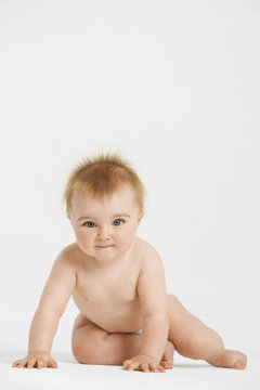 Full length portrait of cute baby with redhead sitting isolated on white background