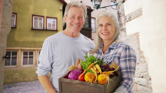 Beautiful white senior couple carrying hand picked vegetables