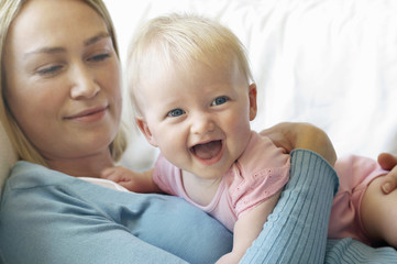 Closeup of a happy baby with mother lying on sofa at home