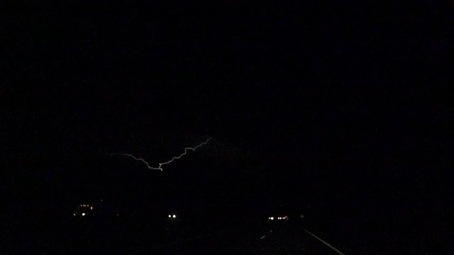 SLOW MOTION: Thunderstorm lightning bolt striking over traffic road