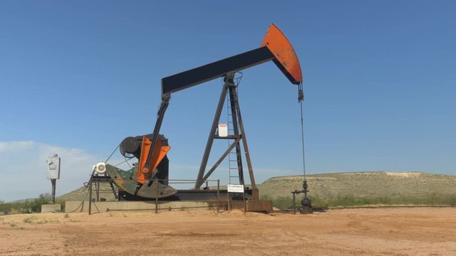 Industrial jack pump platform pumping crude oil in Texas desert