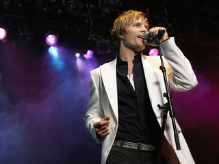 Smart young man singing into microphone on stage