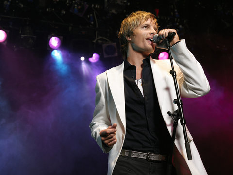 Smart Young Man Singing Into Microphone On Stage