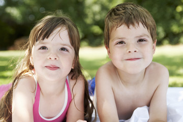 Closeup portrait of a boy and girl lying in the backyard