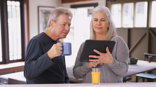 Elderly caucasian couple looking at tablet computer during breakfast