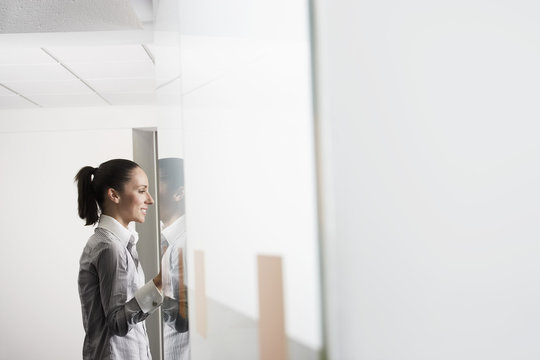 Side View Of Smiling Young Businesswoman Standing In Office Doorway