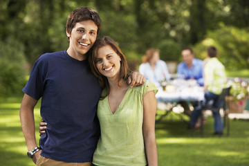 Portrait of happy siblings with family having lunch in background