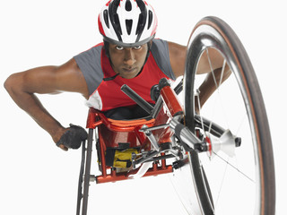 Low angle view of a confident paraplegic cycler against white background