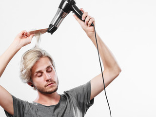Young man drying hair with hairdryer