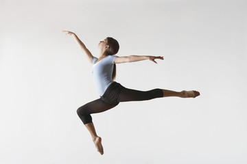 Fototapeta na wymiar Full length of female ballet dancer leaping in mid air isolated on white background