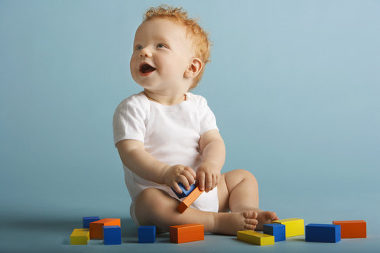 Full Length Of Baby Boy Playing With Building Blocks Isolated On Blue Background