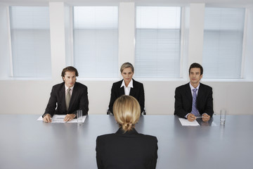 Panel of business people conducting job interview with female candidate