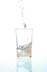 Fresh water pouring in a glass on white background