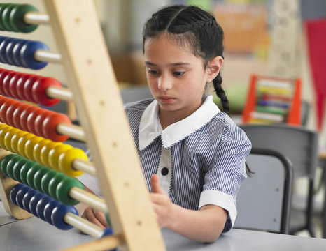 Young girl using abacus in classroom