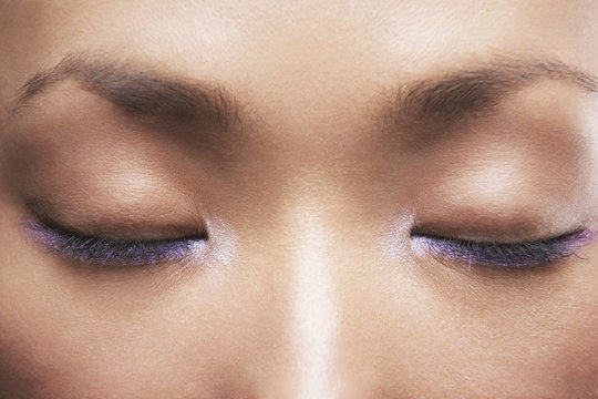 Detail image of beautiful woman with purple eyeliner, eyes closed