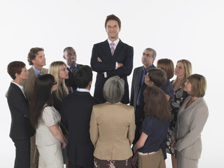 Multiethnic executives around taller businessman against white background