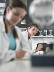 Portrait of a male student working in laboratory with woman in foreground