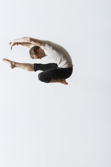Full length of male ballet dancer jumping over white background