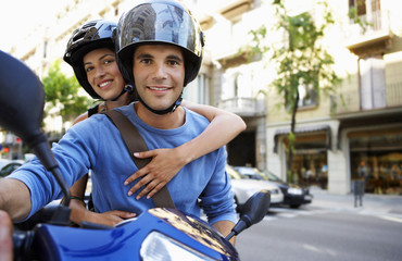 Portrait of happy young couple on scooter enjoying road trip