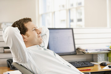 Young businessman reclining in office chair at desk