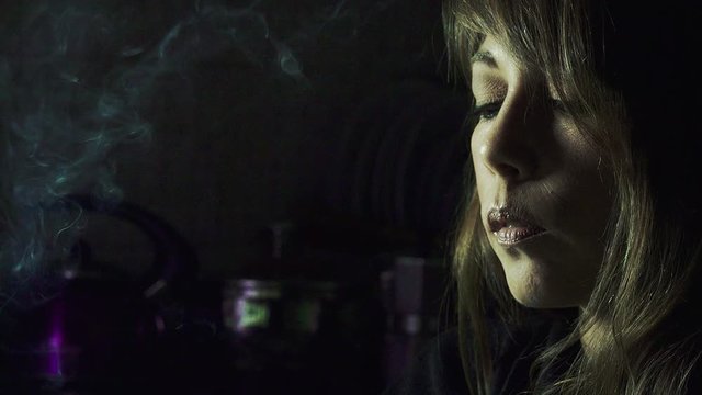 young woman smokes in the night: woman smoking at home