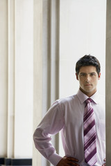 Portrait of serious young businessman standing with hand on hip