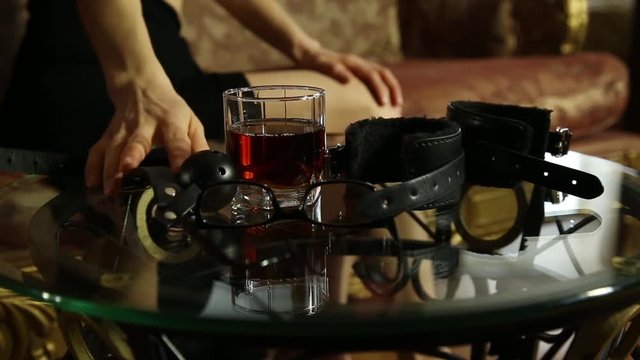 young woman calling on a phone and takes the gag. closeup BDSM accessories and sex toys.