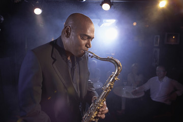 Side view of a musician playing saxophone in jazz club