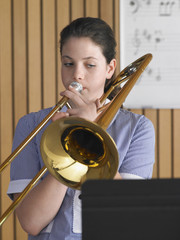 High school girl playing trombone in music class