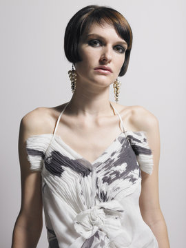 Portrait of a serious elegant woman in dress against gray background