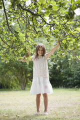 Fototapeta na wymiar Full length portrait of playful young girl holding branches in garden