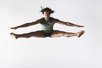 Full length of excited male ballet dancer jumping isolated on white background