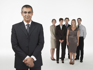 Portrait of a smiling businessman with team against white background
