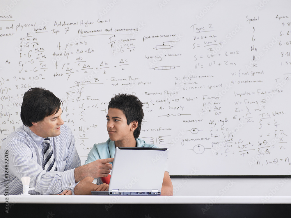 Wall mural teacher and student using laptop sitting in physics classroom