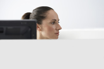 Serious young businesswoman at computer desk looking away