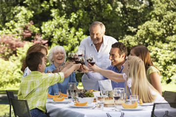 Happy family toasting wine glasses at table in back yard