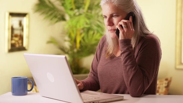 Modern Middle Aged Woman Using Cell Phone And Laptop