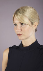 Closeup of a serious blond young businesswoman looking away against purple background