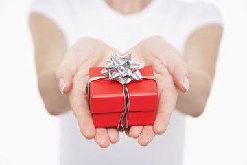 Closeup midsection of a woman holding up small wrapped gift against white background