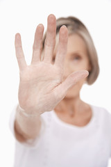 Closeup of a senior woman holding out palm of hand against white background