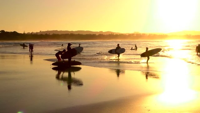SLOW MOTION: Unrecognizable surf people enjoying summer evening surfing in ocean