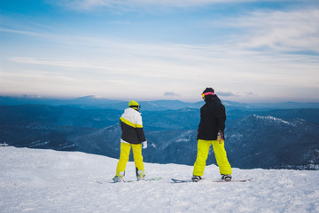 Two sportsmen snowboarders stand and prepare for descent from sn