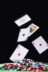 Playing cards falling on pile of gambling chips