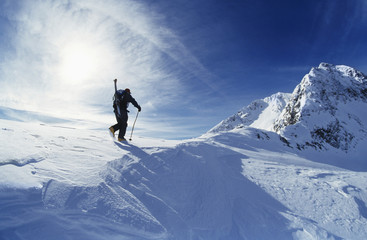Naklejka na ściany i meble Rear view of skier hiking to mountain summit
