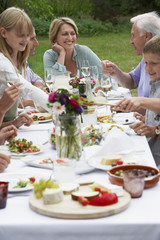 Smiling middle aged woman dining with family in garden