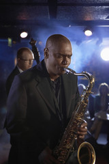 Saxophone player with man playing double bas in background on stage