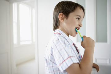 Side view of little boy brushing teeth in bathroom